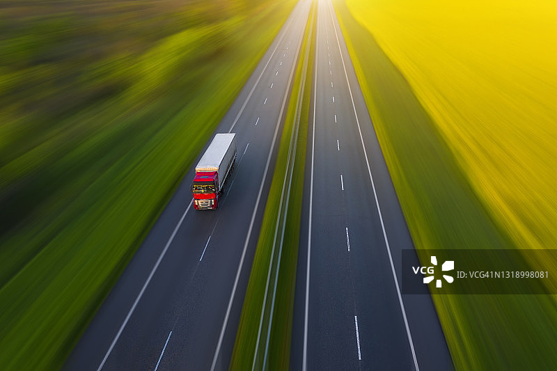 乡村绿色田野中卡车在沥青路上行驶的航拍景色图片素材