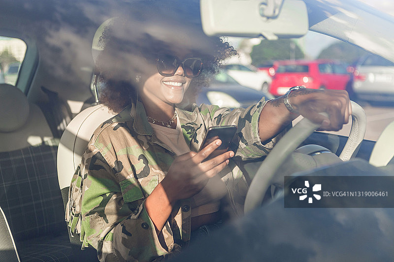 驾驶汽车时使用智能手机的快乐黑人女性图片素材