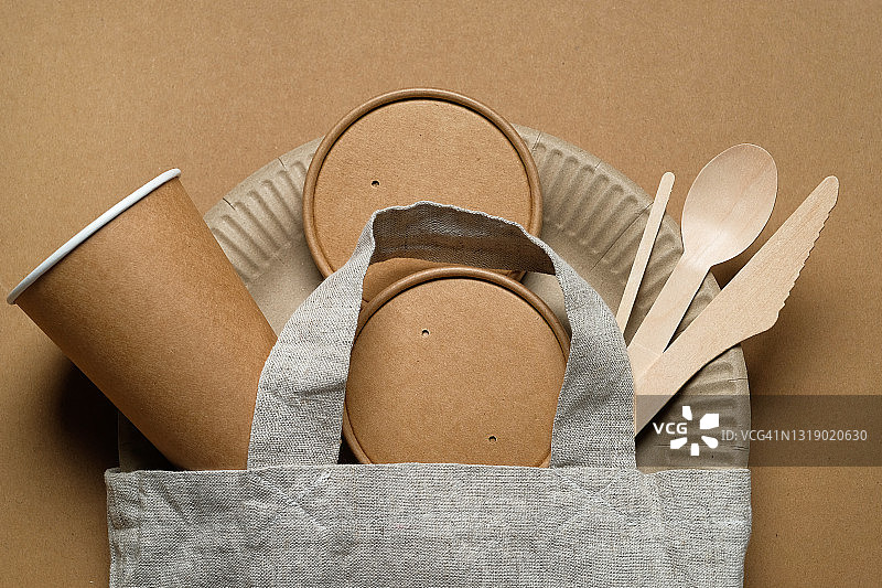 可回收塑料和纸制成的可生物降解一次性餐具。可重复使用的袋子旁边是一个用回收材料制成的网袋。保护、关怀和环境保护的概念。图片素材