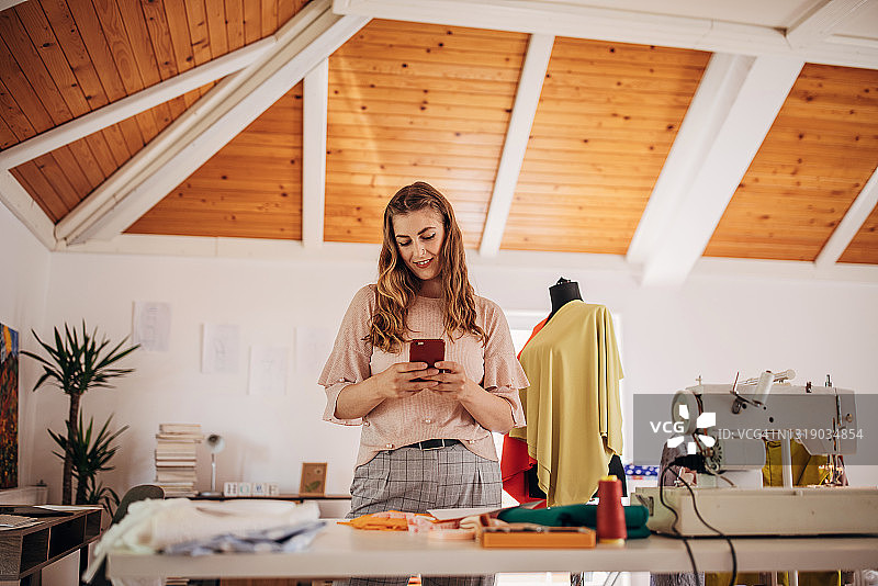 女时装设计师使用智能手机图片素材