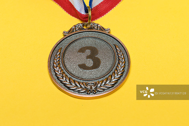 黄色背景上的体育成就铜牌（第三名）图片素材