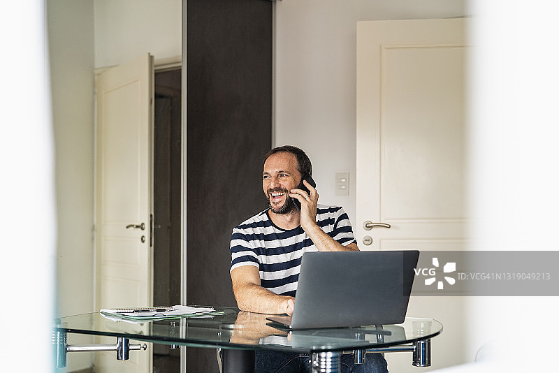中年男子在家工作使用手机的微笑画像图片素材