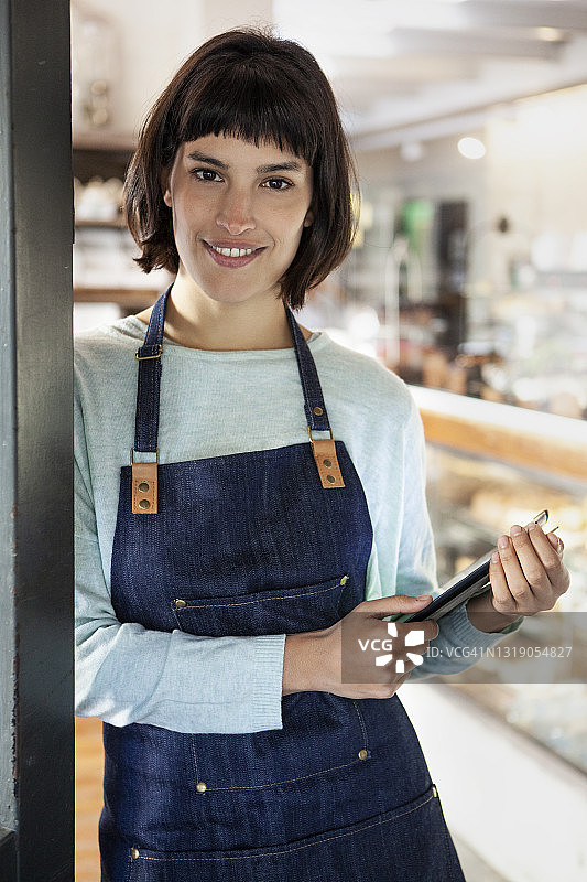 咖啡店里，快乐的女咖啡师在平板电脑上查看内容图片素材