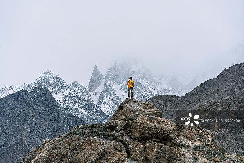 在巴基斯坦北部，一名女子站在雪山背景下的布布里莫廷峰的岩石上图片素材