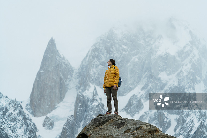 在巴基斯坦北部，一名女子站在雪山背景下的布布里莫廷峰的岩石上图片素材