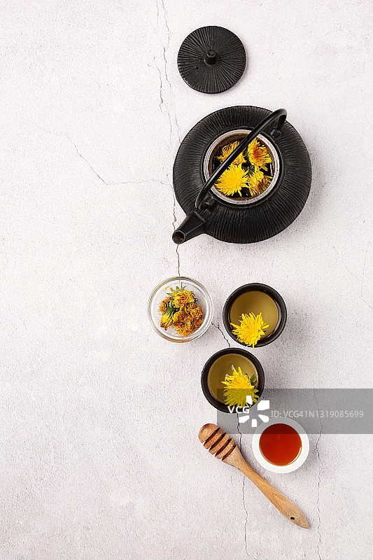 石台上健康的蒲公英草药茶和黑色茶壶图片素材
