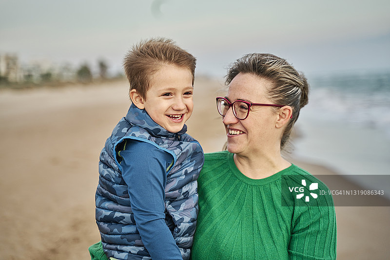 强风中海滩上母亲和儿子的特写图片素材