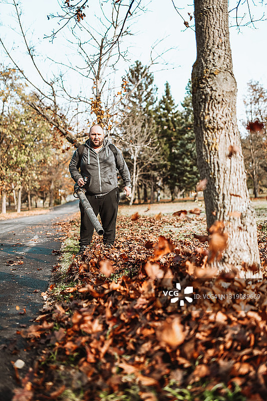 男人在公园里吹落叶图片素材