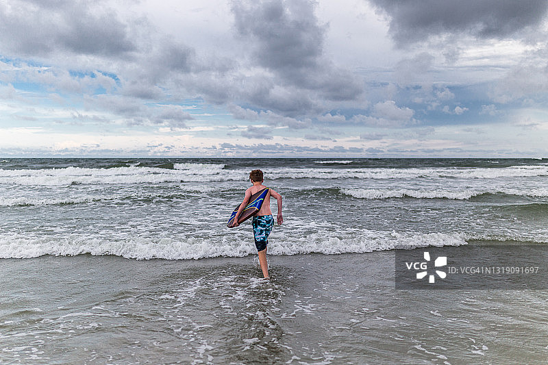 青少年带着趴板冲向大海图片素材