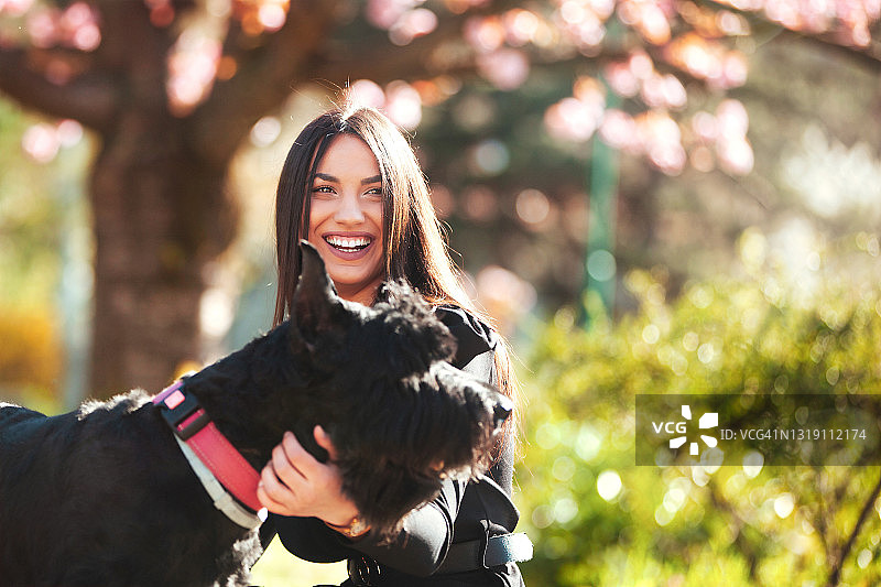 年轻女孩在公园里和她的狗一起微笑图片素材