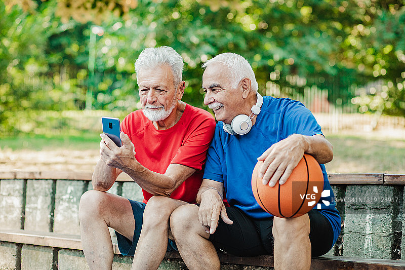 在篮球场上充满活力的老年男士使用手机图片素材
