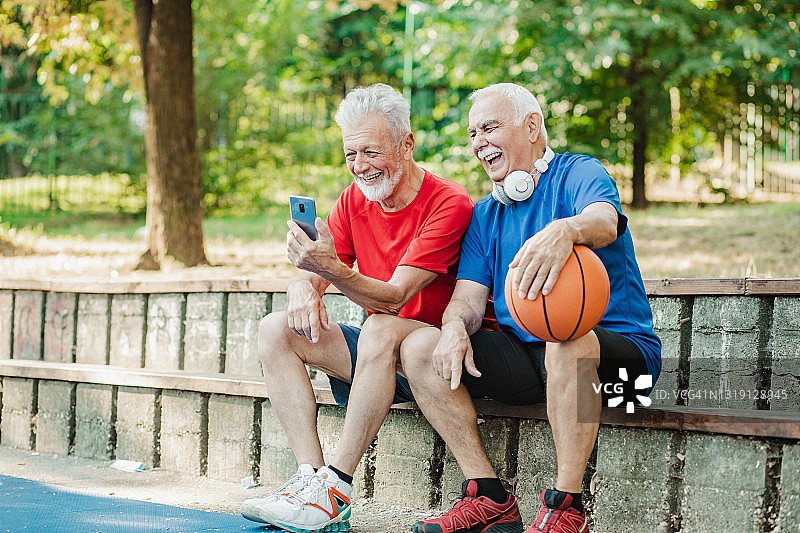 在篮球场上充满活力的老年男士使用手机图片素材