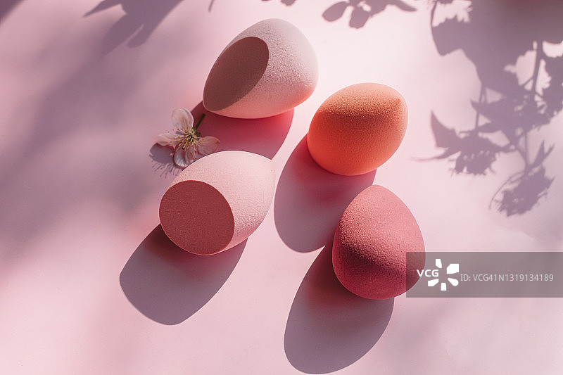 粉色背景上的彩色粉红色和红色化妆海绵图片素材