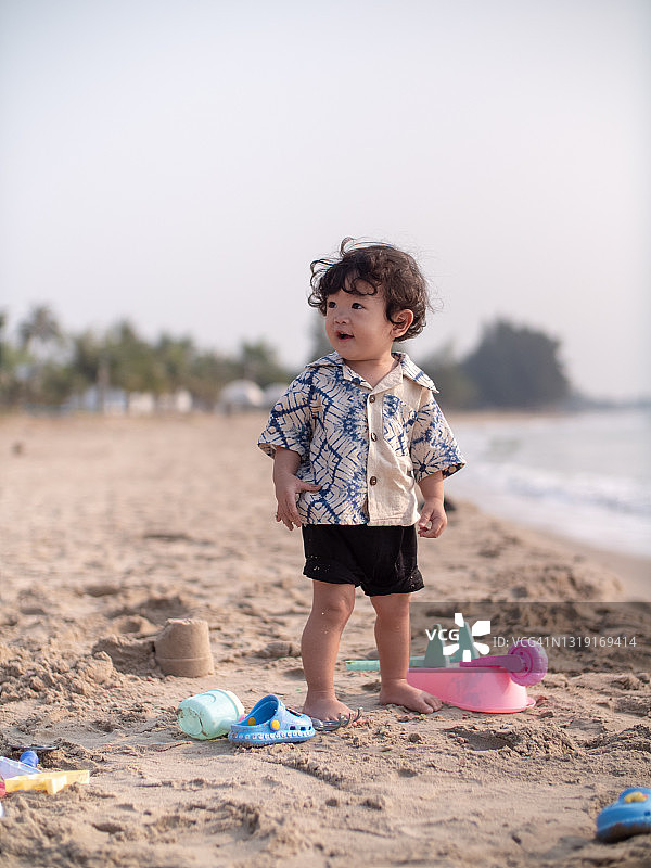 可爱的男孩在沙滩上玩沙子，很开心图片素材