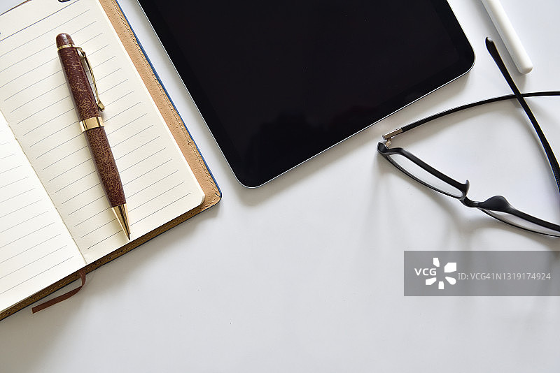现代办公桌顶部视图，含平板电脑、笔记本、触控笔、眼镜，带复制空间图片素材