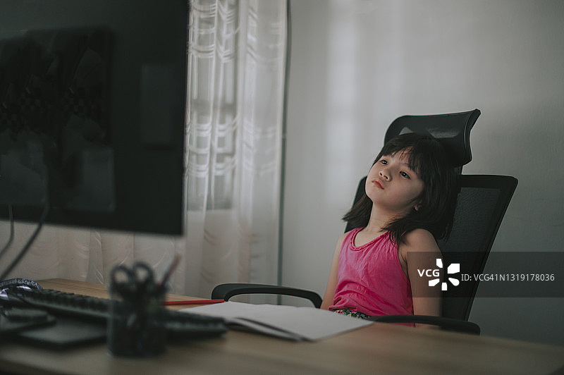 中国女孩在家使用电脑进行线上学习，面露无聊和压力图片素材