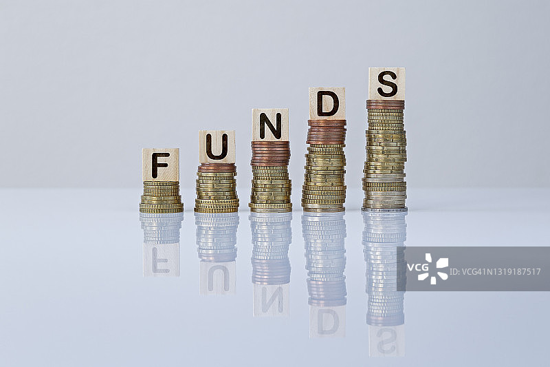 灰色背景下硬币堆上的木块字样“FUNDS”图片素材