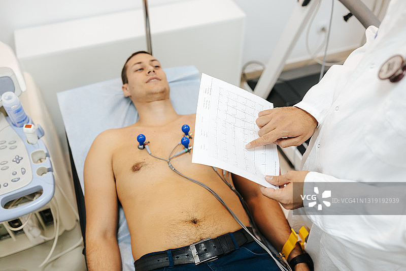 心脏科医生拿着年轻男性患者的心电图图片素材