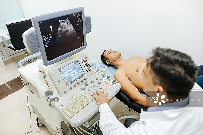 年轻男患者在医疗诊所接受腹部超声检查图片素材