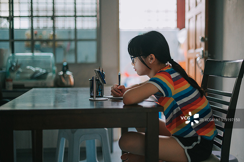 中国年轻女孩在餐厅使用手机上网课，边听边写图片素材
