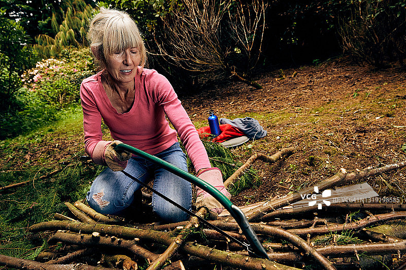 在花园里使用弓锯的女人图片素材
