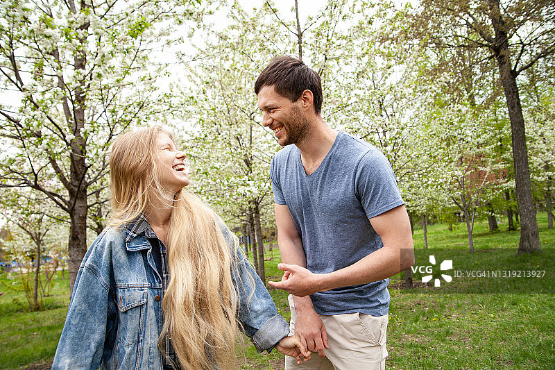 年轻情侣在春天公园里散步图片素材