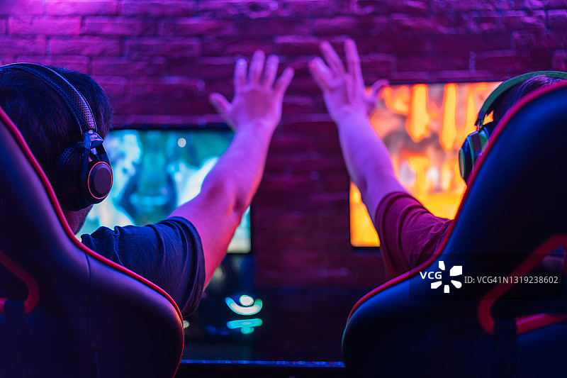 玩电脑游戏并庆祝胜利的亚洲青年男女（背面）图片素材