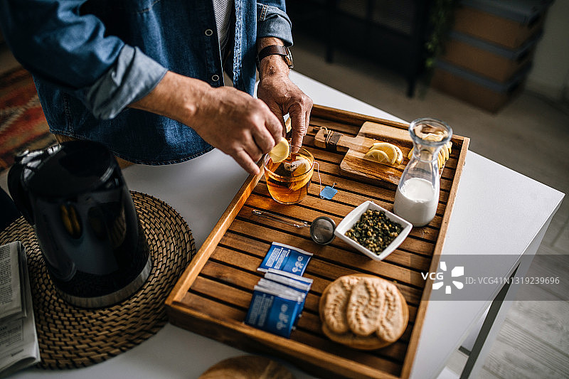 老年男人在厨房柜台上准备热茶图片素材