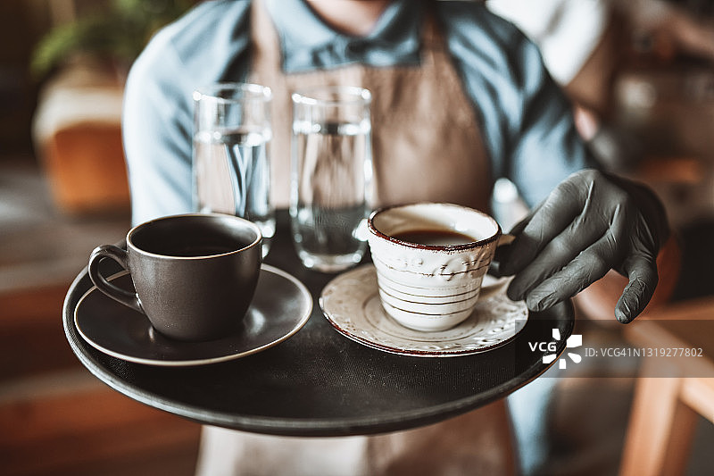 现代服务员为顾客端上咖啡和水图片素材