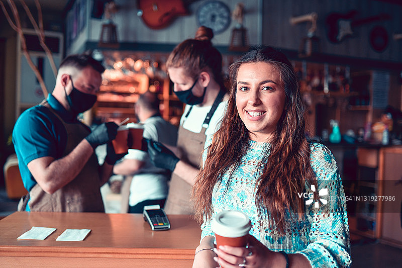 服务员在酒吧通过信用卡与微笑的女顾客确认外卖咖啡订单图片素材