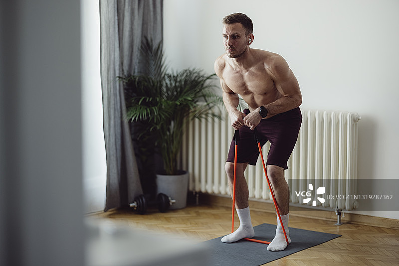 在家用拉力带锻炼的英俊男人图片素材