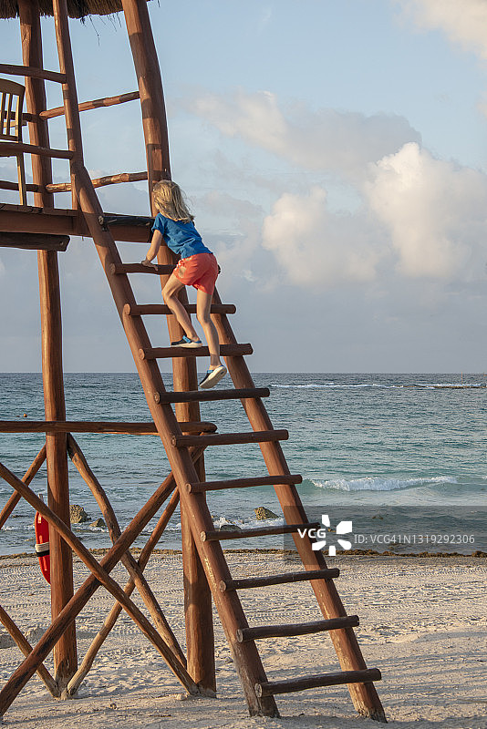 可爱的小男孩在墨西哥玛雅海滨的救生员塔上攀爬图片素材