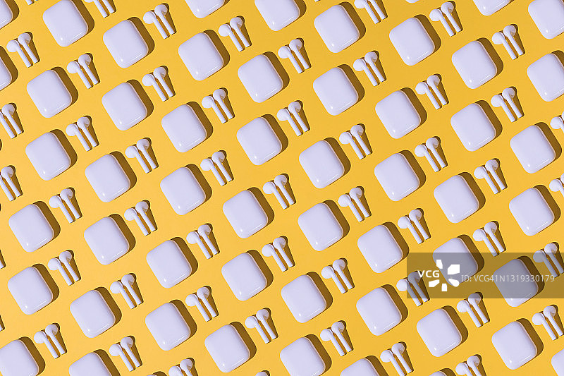 黄色背景上的流行无线白色耳机对角线图案图片素材