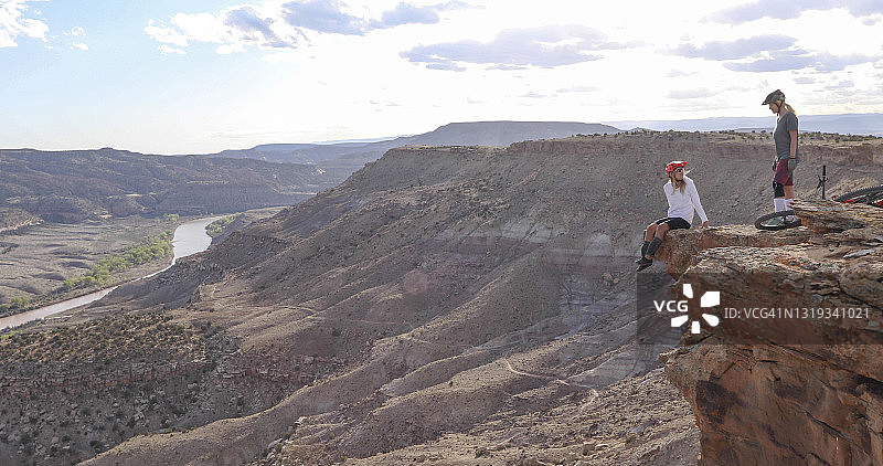 登山自行车手在悬崖边俯瞰峡谷和河流图片素材