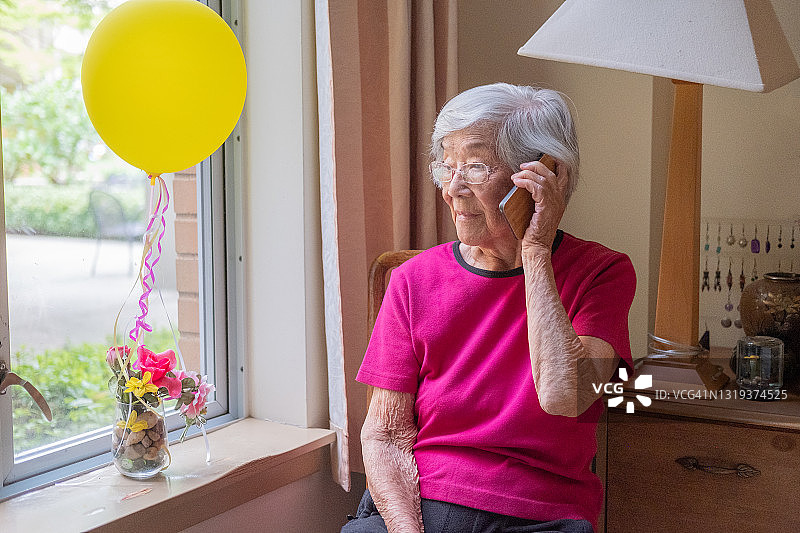 担忧的年长亚裔妇女在家用手机通话图片素材
