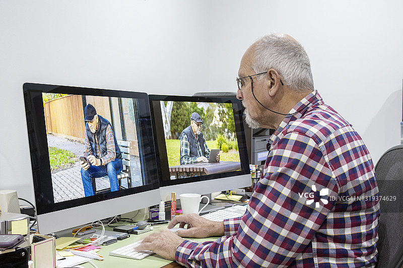 老年男人在家用两台电脑屏幕处理照片图片素材