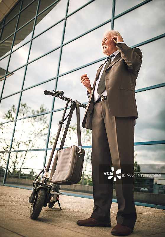 在城市里骑电动滑板车的年长商人图片素材