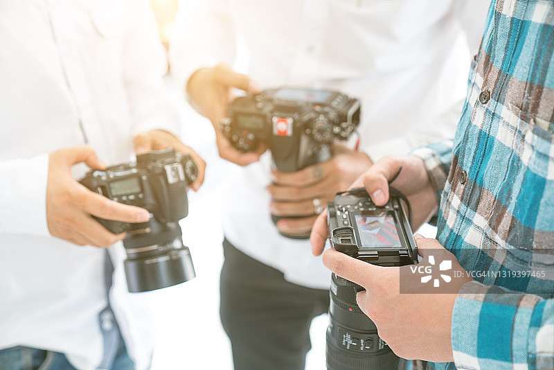 摄影助理协助摄影师挑选照片，青年摄影团队工作图片素材