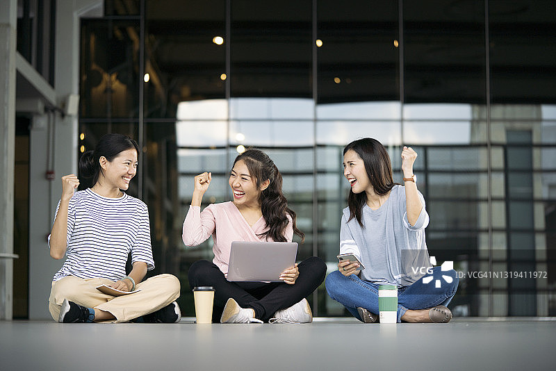 亚洲女孩用笔记本电脑成功学习，感到兴奋和快乐图片素材