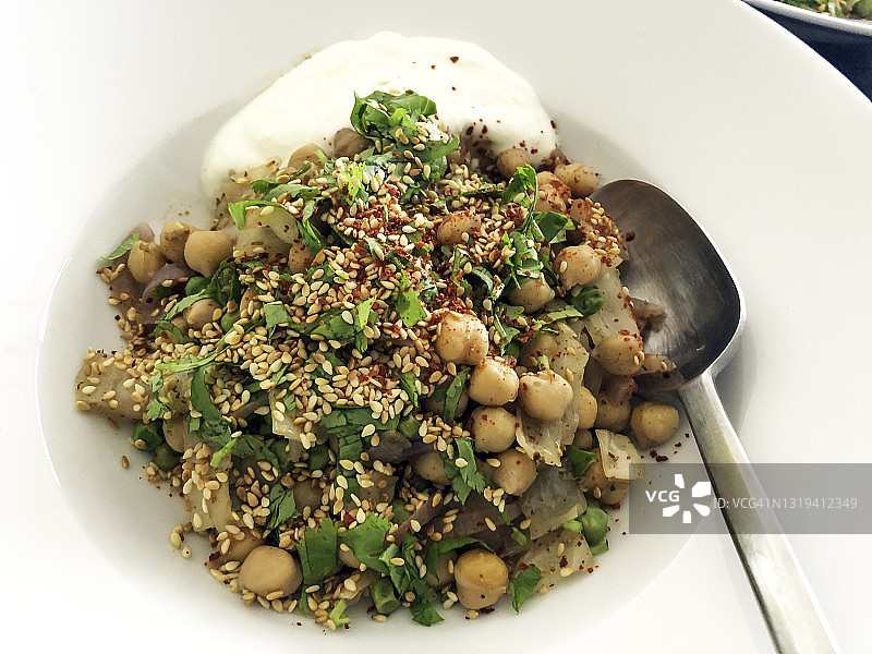 一盘麻辣鹰嘴豆，配有印度综合香料、洋葱、香菜、芝麻和酸奶酱图片素材