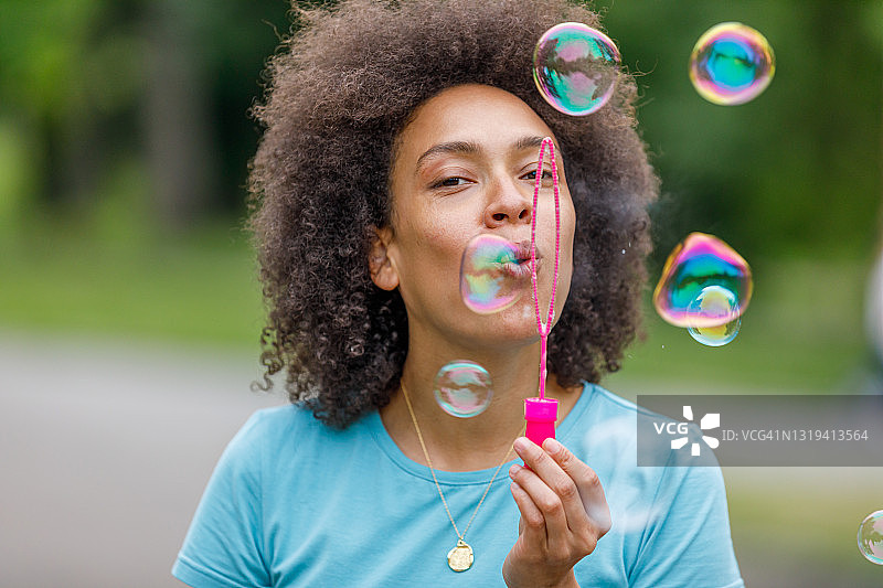 母亲在公园里吹泡泡，享受美好时光。图片素材