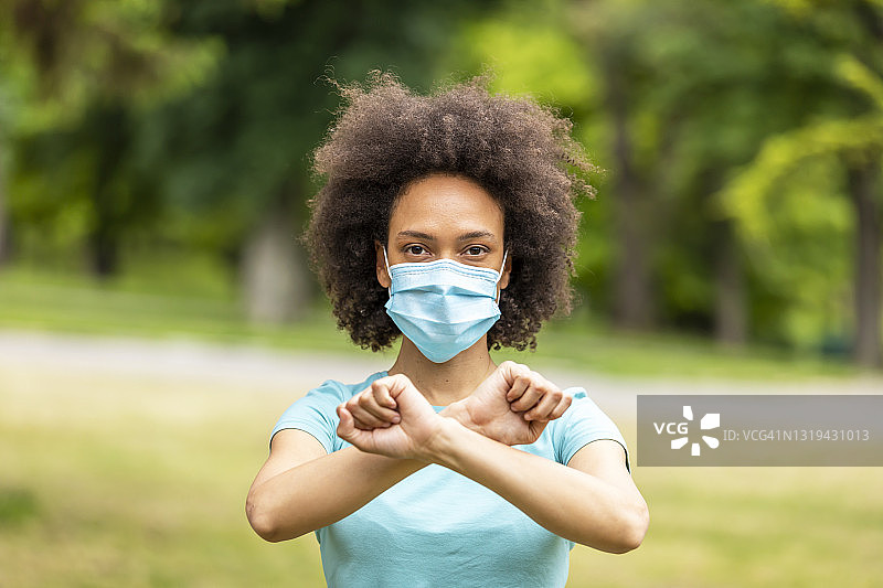 戴着防护口罩的年轻非洲裔女人站在公园里图片素材