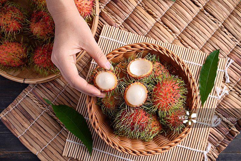 女人手拿食用成熟的红毛丹果图片素材