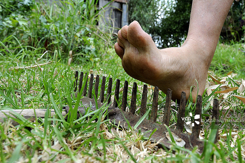 赤脚悬在耙子的尖齿上方，即将踩到图片素材