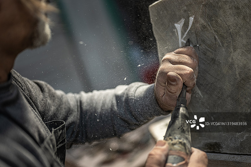 石匠用凿子在石头上雕刻字母的特写图片素材