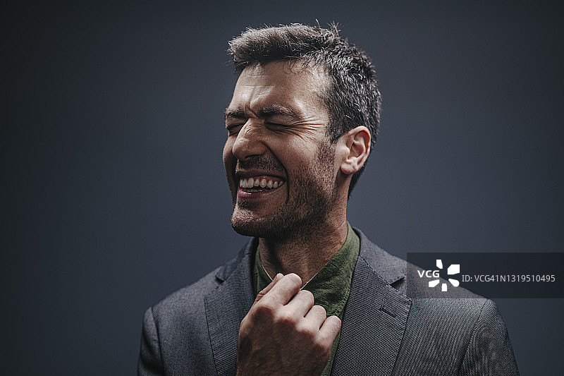深色背景下的英俊微笑男子肖像（工作室拍摄）图片素材