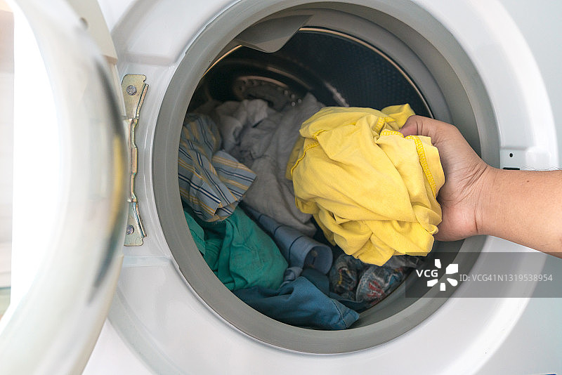 准备洗涤程序。洗衣机、手和衣服图片素材