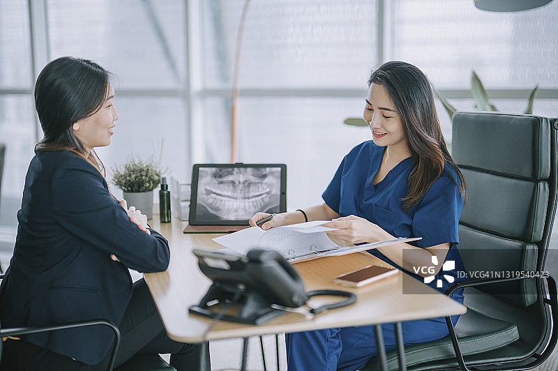 华人女牙医向女患者讲解X光片图片素材