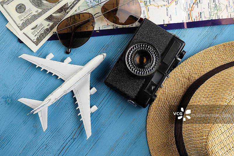 夏季假期用品：相机、太阳镜、现金、草帽、地图和旅行计划、玩具飞机。旅游布局套装和旅行者配件，在木制背景上。开放边界概念，实现自由快乐的旅行。文本空间的副本。图片素材