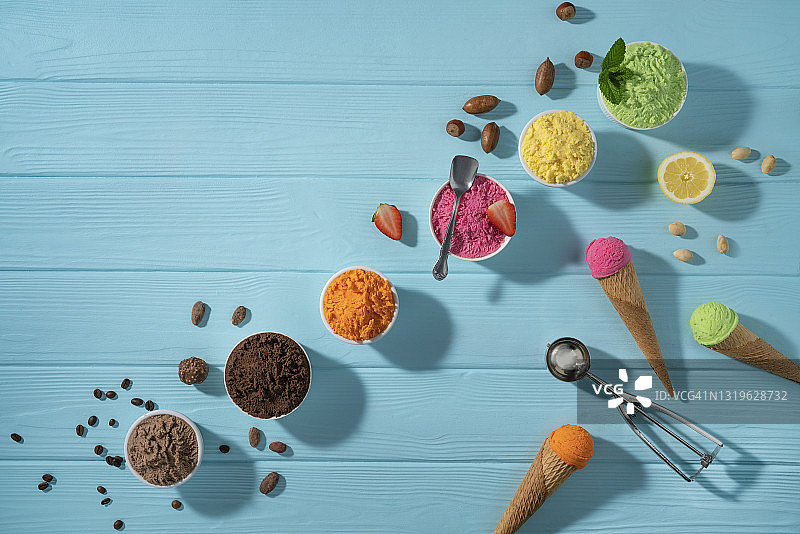 蓝色木纹背景上的什锦冰淇淋杯和华夫饼甜筒图片素材